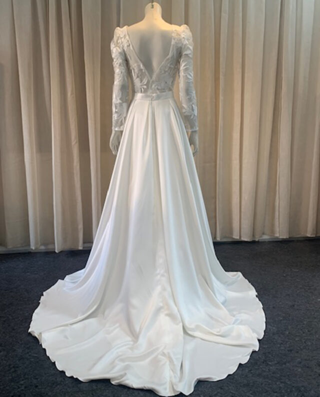 A refined two-piece set featuring a delicate lace top with long sleeves, paired with a flowing duchess satin skirt. Designed by Rikke Gudnitz.