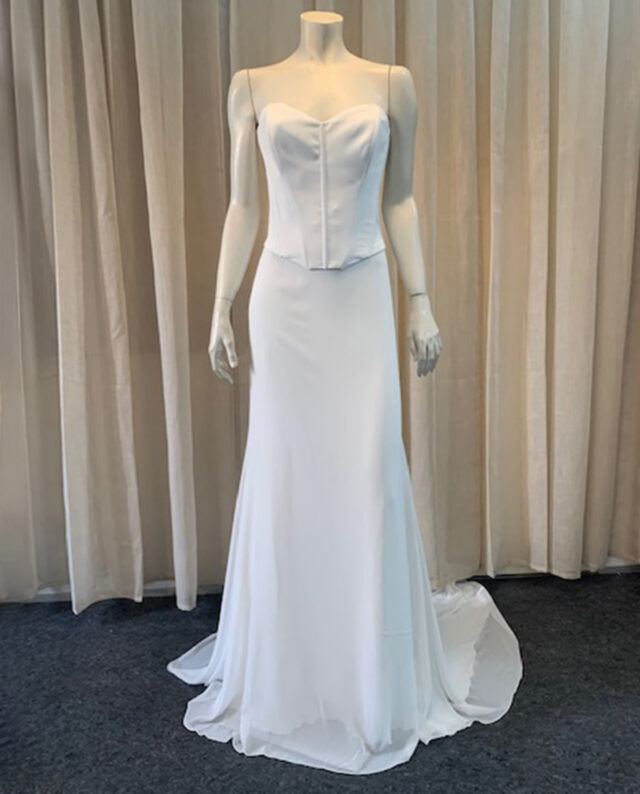 A two-piece dress combining a fitted crepe corset with a graceful chiffon mermaid skirt, creating a timeless and refined bridal look.