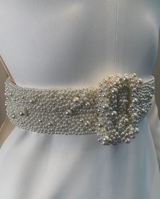 Couture dress in crepe, featuring a handmade beaded pearl belt and a matching pearl-embellished neckline, both crafted with exquisite attention to detail. Designed by Rikke Gudnitz herself.